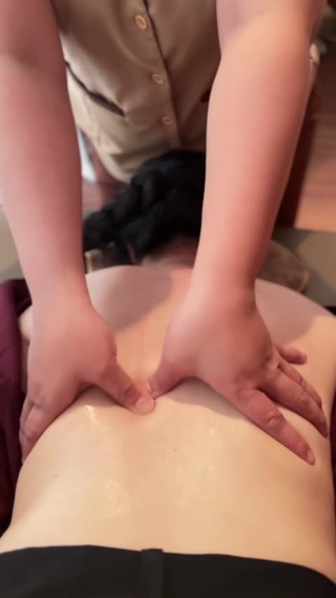 Gốc bàn tay kỹ thuật viên ép dọc hai bên cột sống lưng trên của khách trong buổi massage quận 9 tại Huyệt Đạo Tống Gia, Vinhomes Grand Park