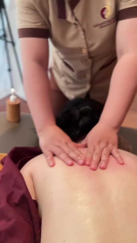 Hai bàn tay kỹ thuật viên chồng lên nhau ép giữa vai khách lớn tuổi trong buổi bấm huyệt Thủ Đức tại Huyệt Đạo Tống Gia Vinhomes Grand Park