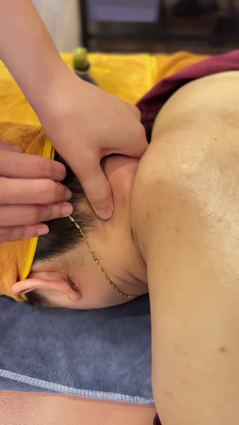 Thumbs pressing points along the side and back of a guest's neck at Tong Gia
