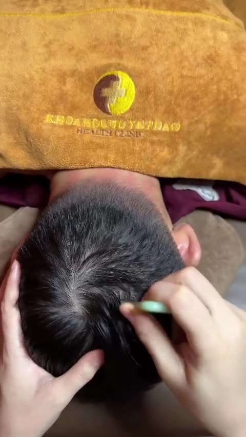 宗家穴道养生技师用绿色梳子从客人头顶向后颈梳刮,做越南头疗