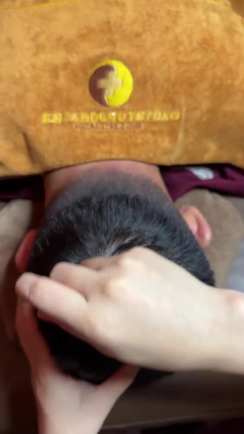 Fingertips pressing into a guest's scalp while the other hand steadies the head during a Vietnamese head spa at Tong Gia