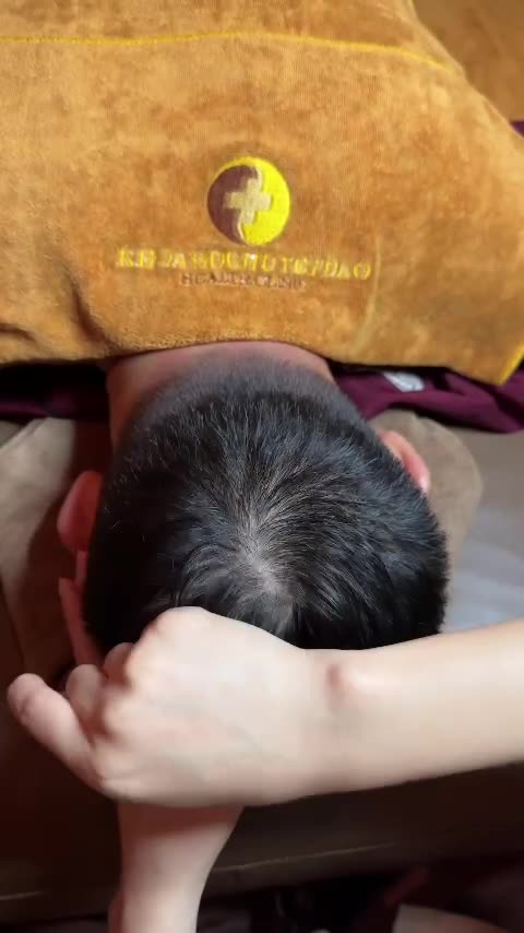 Tong Gia technician pressing both sides of a guest's head, then combing through the hair again