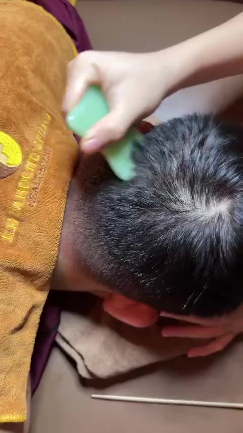 宗家穴道养生技师用绿色梳子在客人后颈与枕部刮痧