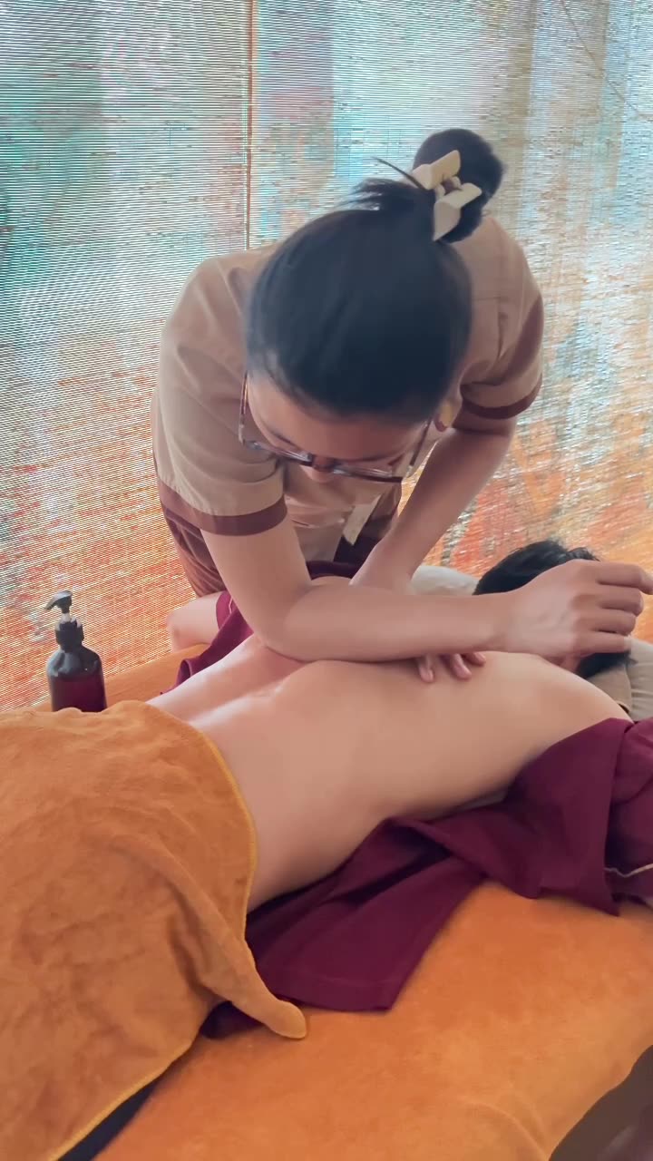 技师俯身,用前臂沿客人背部从上往下推压